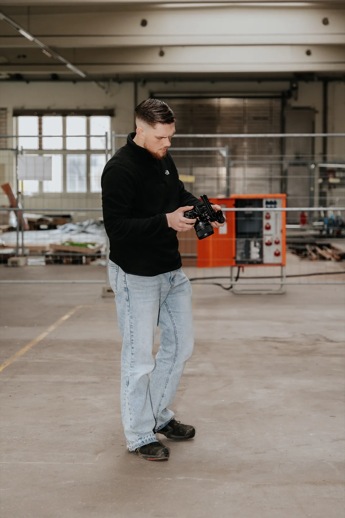 Blick in eine leere Werkshalle, David Schulz filmt seitlich stehend.
