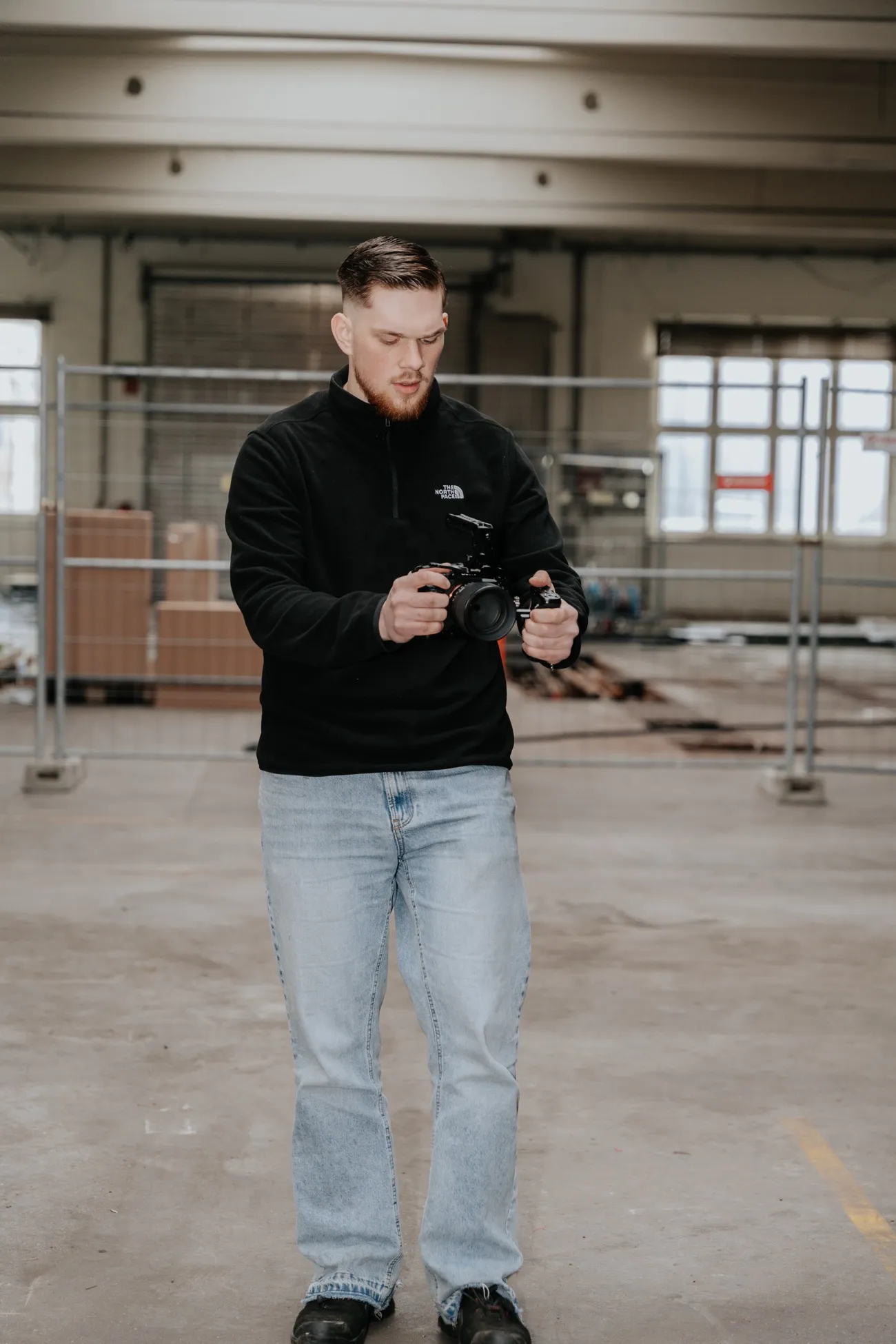 David Schulz steht in der Werkshalle und sieht auf das Display seiner Kamera.